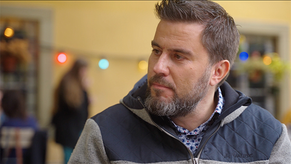 Man in grey jacket sitting outside