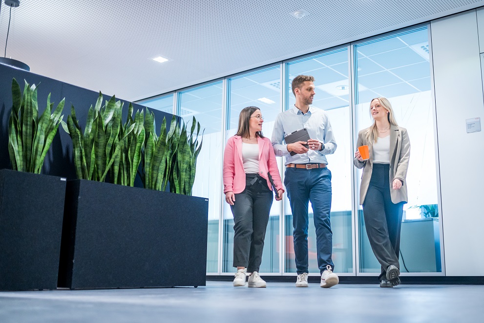 Three people working at STHIL walking along in an office building