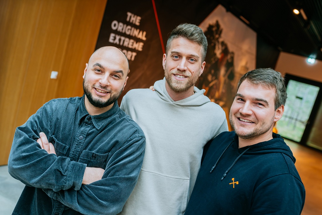 Three men standing in front of a poster 